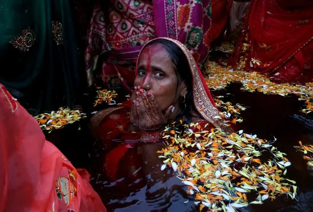 A Hindu woman takes a dip in an artificial pond before she worships the Sun god during the religious festival of Chhath Puja in Mumbai, India, November 10, 2021. (Photo by Niharika Kulkarni/Reuters)