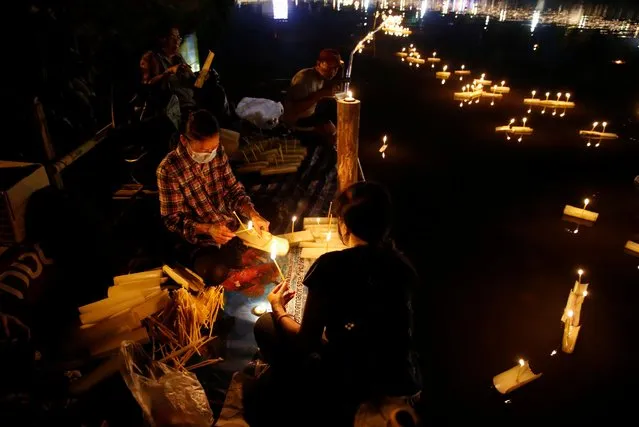 People gather to place krathongs (floating baskets) into a river during the Loy Krathong festival which is held as a symbolic apology to the goddess of the river in Chiang Mai, Thailand, November 19, 2021. Thais believe that the candle-lit boats launched during the charming and popular Loy Krathong festival can carry the year's misfortunes away with them, but workers must clean up the waterways afterward to keep them from getting clogged and polluted. (Photo by Soe Zeya Tun/Reuters)