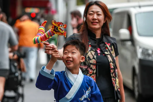 A boy plays with a dragon-shaped puppet as he walks with his parent at Sydney CBD ahead of the Lunar New Year on February 09, 2024 in Sydney, Australia. Lunar New Year, also known as Chinese New Year, is celebrated around the world, and the Year of the Wood Dragon in 2024 is associated with growth, progress, and abundance, as wood represents vitality and creativity, while the dragon symbolizes success, intelligence, and honor. (Photo by Roni Bintang/Getty Images)