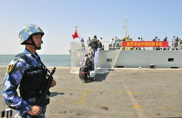 A navy soldier (L) of People's Liberation Army (PLA) stands guard as Chinese citizens board the naval ship “Linyi” at a port in Aden, in this March 29, 2015 file photo. China has launched an unusual charm offensive to explain its first overseas naval base in Djibouti, seeking to assuage global concerns about military expansionism by portraying the move as Beijing's contribution to regional security and development. (Photo by Reuters/Stringer)