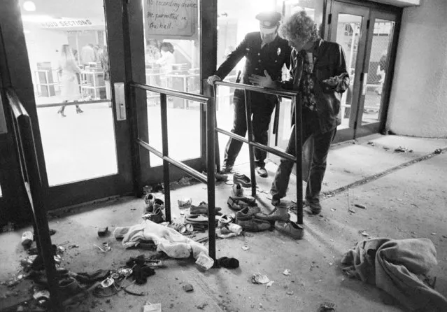 A security guard and an unidentified man look at an area where several people were killed as they were caught in a surging crowd entering Cincinnati's Riverfront Coliseum for a concert by The Who, December 3, 1979. (Photo by Brian Horton/AP Photo)