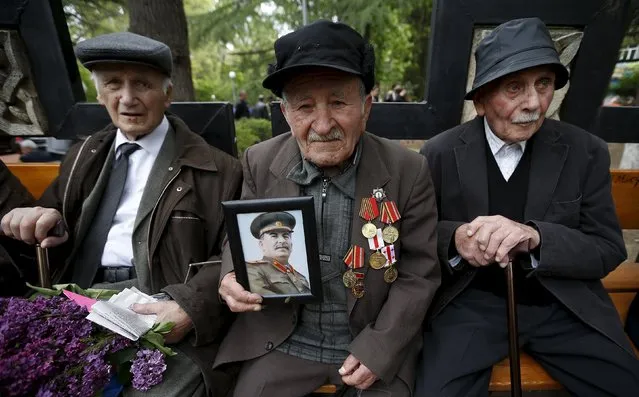 World War Two veterans sit together on a bench as one of them holds up a picture of Joseph Stalin during Victory Day celebrations in Tbilisi, Georgia, May 9, 2015. (Photo by David Mdzinarishvili/Reuters)