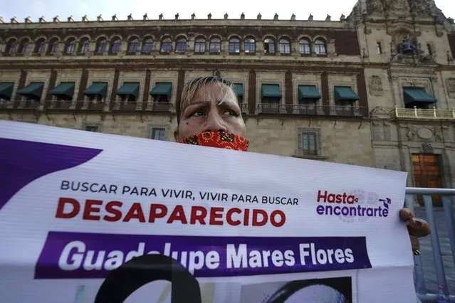 Maria de la Luz Flores holds a sign about her daughter Guadalupe Morales Flores, who she said disappeared on Sept. 7, 2020 before her body was found on March 29, 2021, during a protest demanding answers about people who go missing outside the National Palace in Mexico City, Monday, December 13, 2021. (Photo by Marco Ugarte/AP Photo)