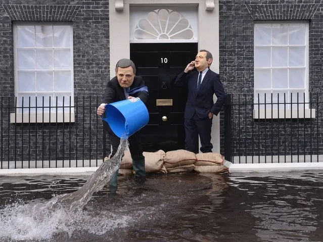 Campaigners dressed as Deputy Prime Minister Nick Clegg (L) and Prime Minister David Cameron pose in front of a mock up of a flooded 10 Downing Street in London, to urge the Prime Minister to act on climate change and to call on politicians to reach agreement on new energy targets at this week's EU Council meeting in Brussels. (Photo by Stefan Rousseau/PA Wire)