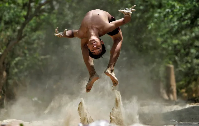 A boy somersaults as he practices diving on the banks of the Yamuna river on a hot summer day in New Delhi, India, April 22, 2016. (Photo by Anindito Mukherjee/Reuters)