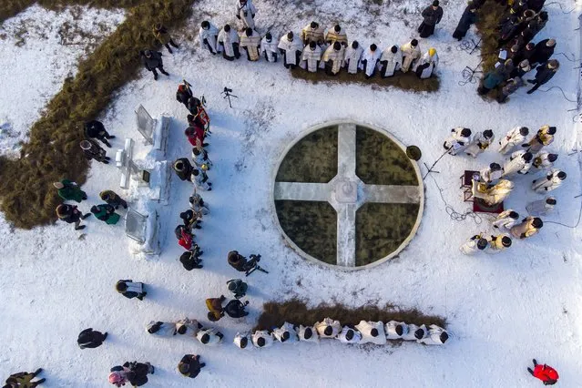 Orthodox priests conduct a religion service blessing the ice water of the Tura river during a traditional Epiphany celebration as the temperature is about –5 degrees (23 degrees Fahrenheit) at the Holy Trinity Monastery in Tyumen, Russia, Tuesday, January 18, 2022. (Photo by Sergei Rusanov/AP Photo)