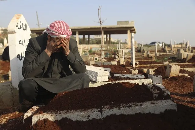 Mohammad al-Mahmoud, father of a seven day old baby Fatima, cries at her grave in Haranbush village, Idlib province, Syria, Wednesday, February 2, 2022. Doctors say Fatima died from cold after she was brought to a hospital from a refugee camp near the village of Haranbush. (Photo by Ghaith Alsayed/AP Photo)