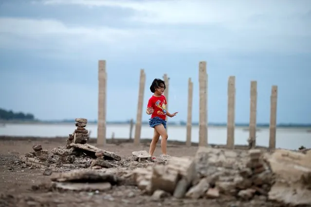 A girl walks through the ruins of a Buddhist temple, which has resurfaced in a dried-up dam due to drought, in Lopburi, Thailand on August 1, 2019. Thousands are flocking to see the Buddhist temple exposed after drought drove water levels to record lows in a dam reservoir where it had been submerged. (Photo by Soe Zeya Tun/Reuters)