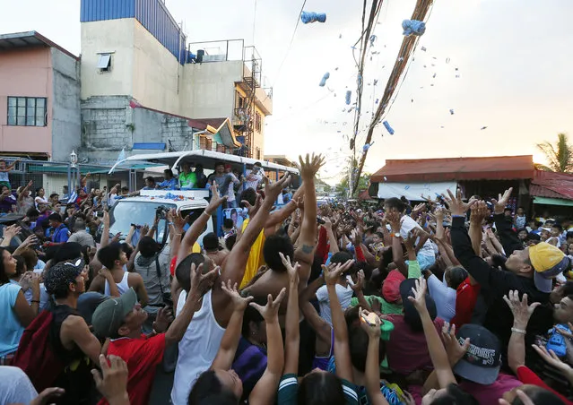 Filipino boxer and Congressman Manny Pacquiao, on board a campaign float, who is running for senator in Monday's national elections throw souvenir t-shirts, candies and wrist bands to supporters during the campaign sortie with Presidential candidate Vice-president Jejomar Binay, in Navotas north of Manila, Philippines Friday, May 6, 2016. (Photo by Bullit Marquez/AP Photo)