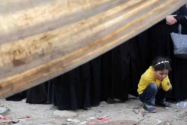 A displaced Iraqi girl waits in a line of women to enter Hammam al-Alil camp, south of Mosul, Iraq, April 8, 2017. (Photo by Andres Martinez Casares/Reuters)