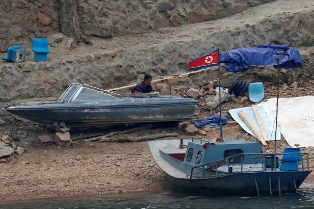 A North Korean man fixes a boat on the banks of the Yalu River in Sinuiju, North Korea, which borders Dandong in China's Liaoning province, April 16, 2017. (Photo by Aly Song/Reuters)