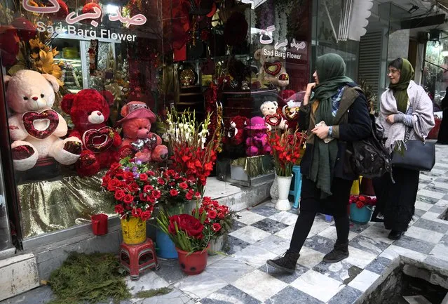 Afghan women pass a flower shop decorated for Valentine's Day in Kabul, Afghanistan, Sunday, February 13, 2022. (Photo by Hussein Malla/AP Photo)