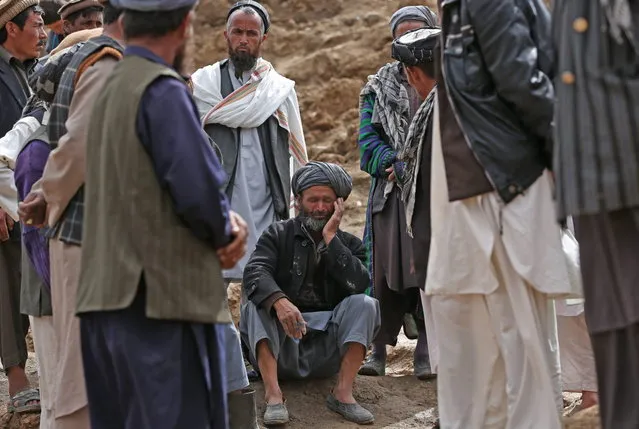 Survivors pray for their lost at the site of Friday's landslide that buried part of Abi Barik village in Badakhshan province, northeastern Afghanistan, Monday, May 5, 2014. The landslide was likely triggered by heavy rains that have fallen across northern Afghanistan in recent weeks. It broke off such a massive chunk of earth, burying hundreds of homes, that officials have said it will be impossible to bring up all the bodies. Still, many villagers have continued digging on their own. (Photo by Massoud Hossaini/AP Photo)