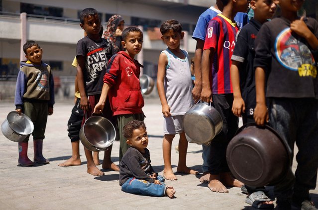 Palestinian children gather to receive food cooked by a charity kitchen, amid food scarcity, as Israel-Hamas conflict continues, in Khan Younis in the southern Gaza Strip, on June 26, 2024. (Photo by Mohammed Salem/Reuters)