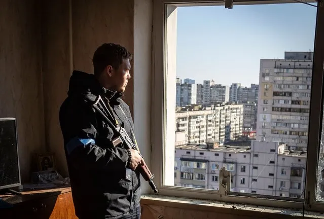 A police officer looks through the window of a damaged flat in a residential building which was hit by the debris from a downed rocket in Kyiv on March 17, 2022. One person was killed and three injured when debris from a downed rocket hit a Kyiv apartment block, as Russian forces press in on the capital, emergency services said. Russian troops trying to encircle Kyiv have launched early morning strikes on the city for several successive days, putting traumatised residents further on edge. (Photo by Fadel Senna/AFP Photo)