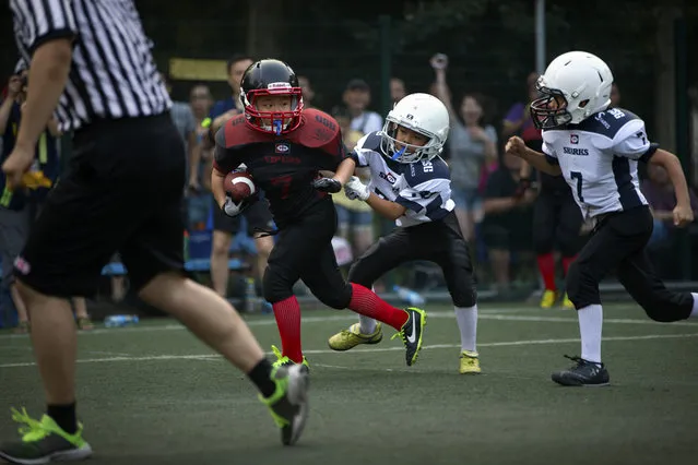 In this Sunday, July 5, 2015 photo, a young player dodges a pair of opposing tacklers during their American football game in Beijing. (Photo by Mark Schiefelbein/AP Photo)