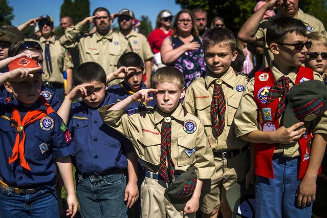 Eli Whalen, 10, center, purses his lip as he salutes the lives of fallen soldiers who have made the ultimate sacrifice dying for their country in battle while paying his respects alongside fellow Boy Scouts and Cub Scouts alike on Memorial Day amidst hundreds of families attending a ceremony on Monday, May 29, 2017 at Fairview Cemetery in Linden, Mich. (Photo by Jake May/AP Photo)