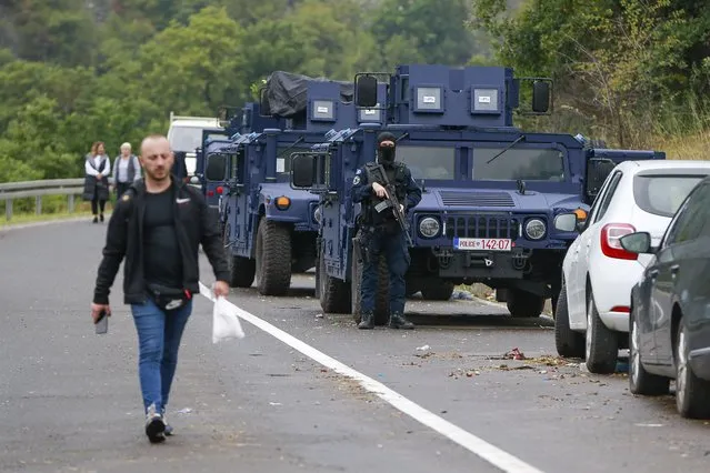 An ethnic Serb walks past Kosovo police securing the area near the northern Kosovo border crossing of Jarinje on the ninth day of protest on Tuesday, September 28, 2021. Ethnic Serbs in Kosovo have been blocking the border for a ninth straight day to protest a decision by Kosovo authorities to start removing Serbian license plates from cars entering the country, raising fears such incidents could unleash much deeper tensions between the two Balkan foes. (Photo by Visar Kryeziu/AP Photo)