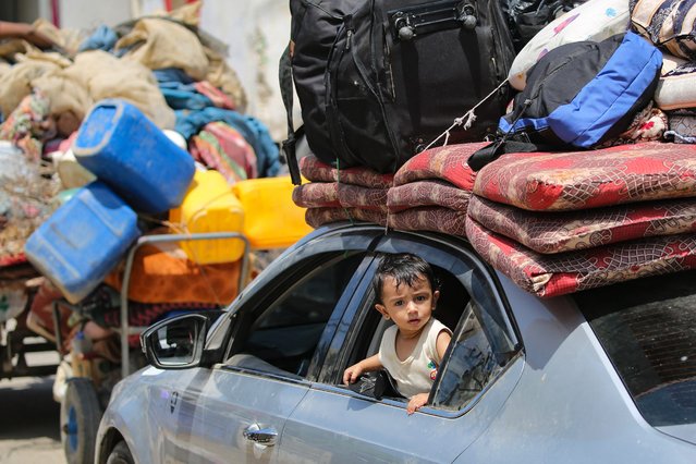 A child peeks out from the window of a car as Palestinians flee with their belongings Deir el-Balah in the central Gaza Strip on August 16, 2024, amid the ongoing conflict between Israel and the Hamas militant group. (Photo by Eyad Baba/AFP Photo)