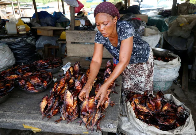 A woman prepares smoked fish for sale at a marketplace in Libreville, Gabon, February 3, 2017. (Photo by Mike Hutchings/Reuters)