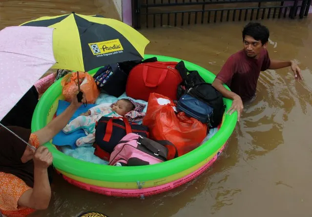 A baby is evacuated by a rescue team using an inflatable boat after floods hit a residential area in Tangerang, near Jakarta, Indonesia, January 1, 2020. (Photo by Muhammad Iqbal/Antara Foto via Reuters)