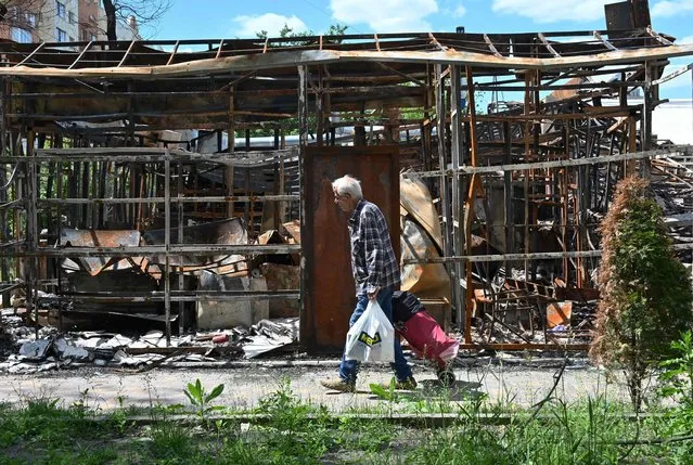 A man walks past a destroyed shop in northern outskirts of Kharkiv on June 7, 2022, amid the Russian invasion of Ukraine. (Photo by Sergey Bobok/AFP Photo)