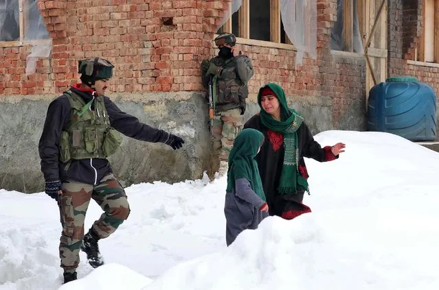 A woman cries as she walks past Indian soldiers near the site of a gun battle between suspected militants and Indian security forces at Bathen village in south Kashmir's Awantipora town January 21, 2020. (Photo by Younis Khaliq/Reuters)