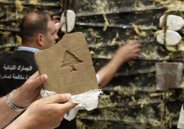 A Lebanese customs employee displays a packet of confiscated hashish stamped with a Lebanese cedar in Beirut May 27, 2009. Lebanese Internal Security forces and Lebanese Customs anti-drugs trafficking division seized a total of 85 kg (187 lbs) of hashish hidden in a refrigerated container that was supposed to be smuggled into the Netherlands. (Photo by Mohamed Azakir/Reuters)