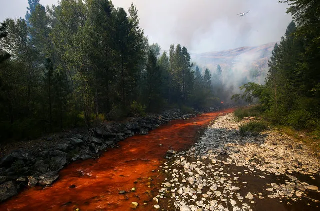 The Twisp River is turned a deep red after an aerial drop of fire retardant landed in the river as a fire flared up near Twisp, Wash., Thursday, August 20, 2015. Authorities warned that more high winds Thursday could make conditions very challenging. (Photo by Joshua Trujillo/seattlepi.com via AP Photo)
