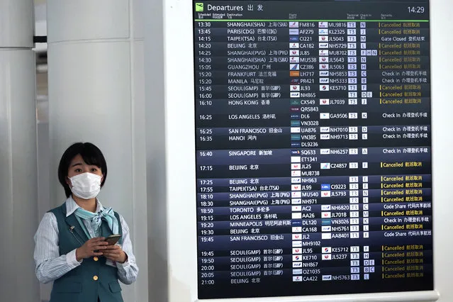 Airline staff stands next to a flight schedule board showing numerous canceled flights due to the coronavirus at the Haneda International Airport in Tokyo, Wednesday, March 18, 2020. For most people, the new coronavirus causes only mild or moderate symptoms. For some it can cause more severe illness, especially in older adults and people with existing health problems. (Photo by Eugene Hoshiko/AP Photo)