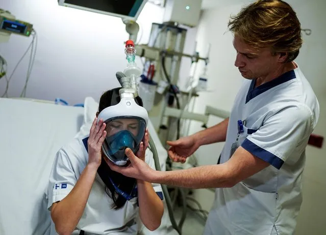 A medical worker tests a Decathlon snorkeling mask upgraded with 3D-printed respiratory valves fittings on March 27, 2020 at the Erasme Hospital in Brussels, during a national lockdown in Belgium to curb the spread of COVID-19 (novel coronavirus). (Photo by Kenzo Tribouillard/AFP Photo)
