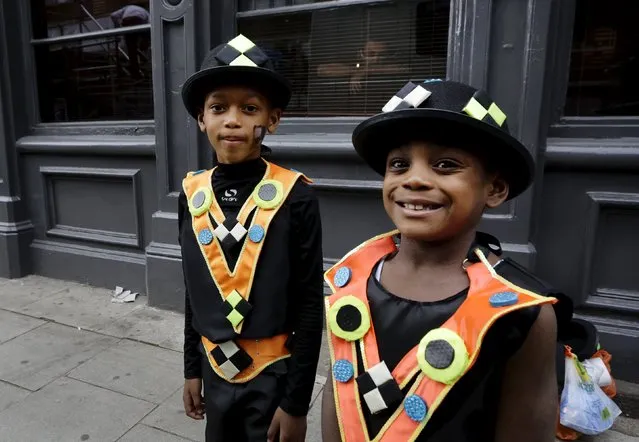 Boys in costume pose for a picture as a man look from a window at the Notting Hill Carnival in London, Britain, August 30, 2015. (Photo by Kevin Coombs/Reuters)