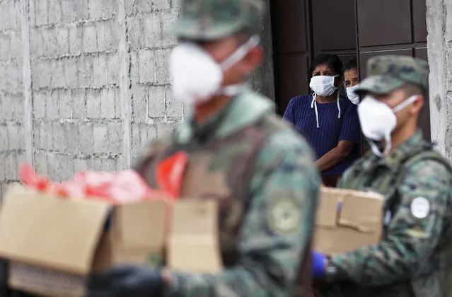 Soldiers distribute food to people who cannot leave their homes during the lockdown enacted to help contain the spread of the new coronavirus in Quito, Ecuador, Thursday, April 2, 2020. (Photo by Dolores Ochoa/AP Photo)