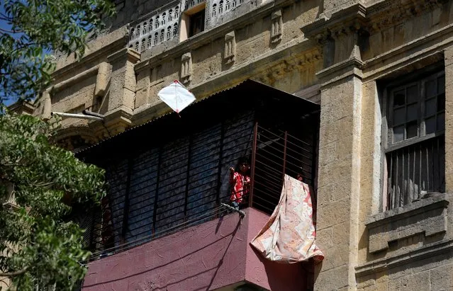 A boy flies a kite from the balcony of his family house during a lockdown after Pakistan shut all markets, public places and discouraged large gatherings amid an outbreak of coronavirus disease (COVID-19), in Karachi, Pakistan, April 1, 2020. (Photo by Akhtar Soomro/Reuters)