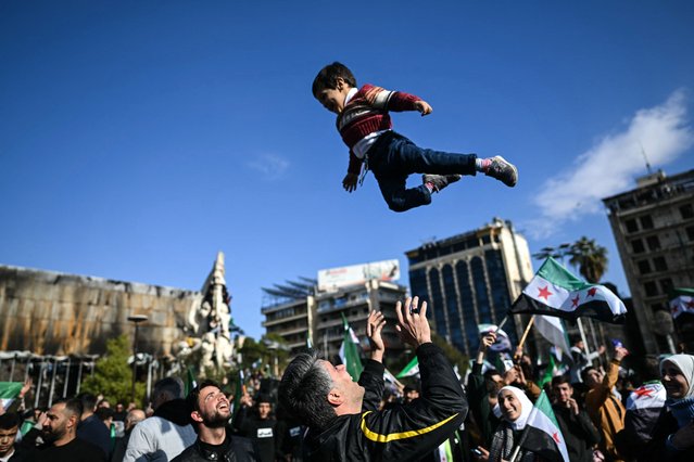 A man joyfully tosses a boy into the air as people gather at Saadallah al-Jabiri Square after the Friday noon prayer in Aleppo on December 13, 2024, to celebrate the ousting of president Bashar al-Assad and the end of five decades of Baathist rule in the country. More than half a century of brutal rule by the Assad clan came to a sudden end on December 8, after a lightning rebel offensive swept across the country and took the capital. (Photo by Ozan Kose/AFP Photo)