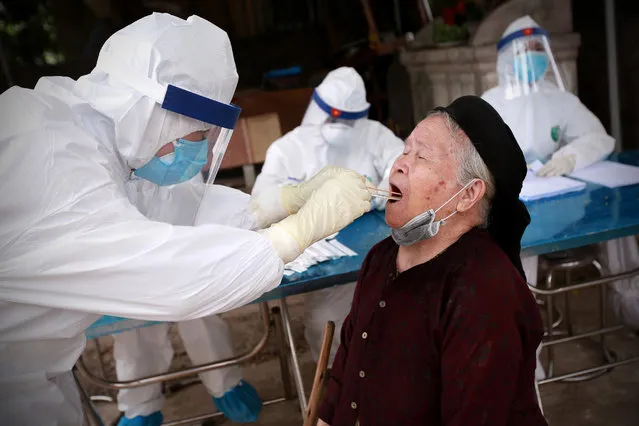 A medical staff in protective gear collects a swab sample from a resident of Ha Loi village, in Hanoi, Vietnam, 11 April 2020. The village, which is home to nearly 11,000 people, started a 28-day quarantine period on 08 April 2020, after a resident was confirmed being infected with coronavirus. (Photo by Luong Thai Linh/EPA/EFE/Rex Features/Shutterstock)