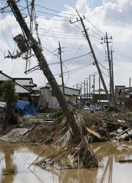 Local residents walk near the site where destroyed street and electric power poles at a residential area flooded by the Kinugawa river, caused by typhoon Etau, in Joso, Ibaraki prefecture, Japan, September 11, 2015. (Photo by Issei Kato/Reuters)
