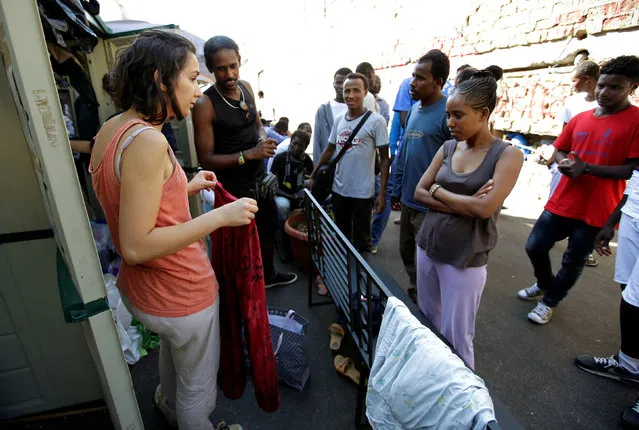 Migrants receive clothes from volunteers at a makeshift camp in Via Cupa (Gloomy Street) in downtown Rome, Italy, August 1, 2016. (Photo by Max Rossi/Reuters)