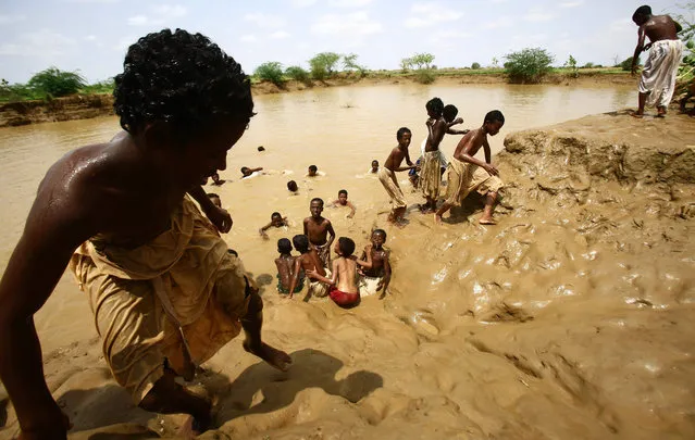 Sudanese children play in mud in the village of Makli that was flooded as the river Gash burst its banks on August 14, 2016, in the impoverished eastern state of Kasala bordering Eritrea. Thousands of houses have been destroyed and several villages submerged after flooding triggered by torrential rainfall killed 100 people across Sudan, officials and an AFP photographer said. (Photo by Ashraf Shazly/AFP Photo)
