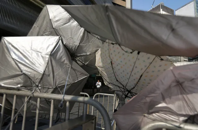 A man is framed by a barricade made of metal gates and umbrellas in the central financial district, Tuesday, September 30, 2014, in Hong Kong. Students and activists, many of whom have been camped out since late Friday, spent a peaceful night singing as they blocked streets in Hong Kong in an unprecedented show of civil disobedience to push demands for genuine democratic reforms. (Photo by Wong Maye-E/AP Photo)