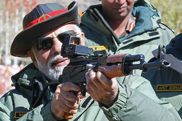 This handout photograph taken on October 24, 2022 and released by the Indian Press Information Bureau (PIB) shows India's Prime Minister Narendra Modi holding a rifle while meeting with the members of Indian armed forces on the occasion of Diwali, the Hindu festival of lights, at Kargil. (Photo by PIB/AFP Photo)