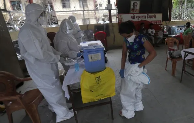 A health worker removes her personal protective equipment after completing screening of residents for COVID-19 symptoms in Dharavi, one of Asia's biggest slums, in Mumbai, India, Friday, June 26, 2020. India is the fourth hardest-hit country by the pandemic in the world after the U.S., Russia and Brazil. (Photo by Rafiq Maqbool/AP Photo)