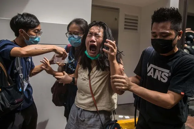 A woman reacts after she was hit with pepper spray deployed by police as they cleared a street with protesters rallying against a new national security law in Hong Kong on July 1, 2020, on the 23rd anniversary of the city's handover from Britain to China. A man found in possession of a Hong Kong independence flag became the first person to be arrested under Beijing's new national security law for the city, police said on July 1. (Photo by Dale De La Rey/AFP Photo)