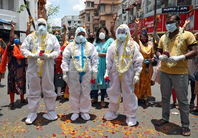 Healthcare workers wearing Personal Protective Equipment (PPE) are showered with flower petals by the residents to show gratitude towards the frontline workers fighting the coronavirus disease (COVID-19) outbreak, on the occasion of National Doctor's Day in Kolkata, India, July 1, 2020. (Photo by Rupak De Chowdhuri/Reuters)