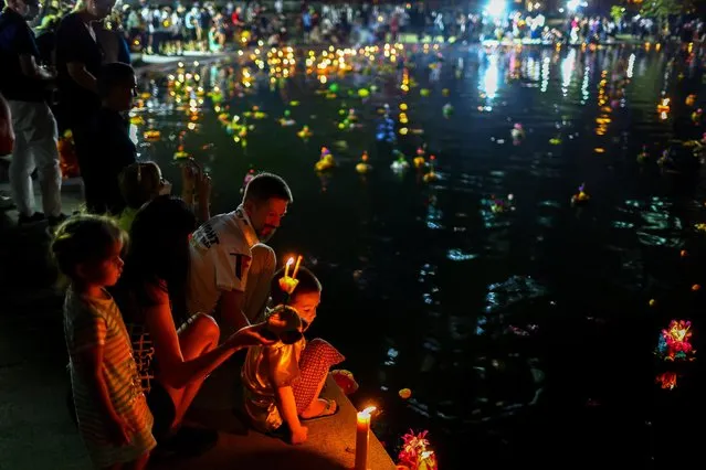 People pray before casting krathongs into a pond at a public park during the Loy Krathong festival which is held as a symbolic apology to the goddess of the river in Bangkok, Thailand on November 8, 2022. (Photo by Athit Perawongmetha/Reuters)