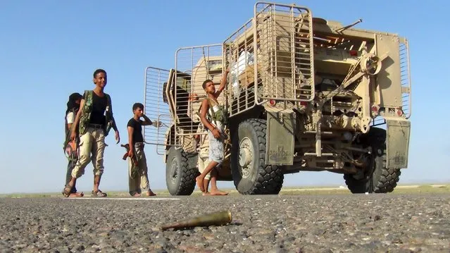 Militants loyal to Yemen's government stand next to an armoured vehicle at the frontline to fight against Houthi militants in control of the Bab al-Mandab Strait, which links the Red Sea to the Gulf of Aden, in the Yemeni governorate of Taiz, October 3, 2015. (Photo by Reuters/Stringer)