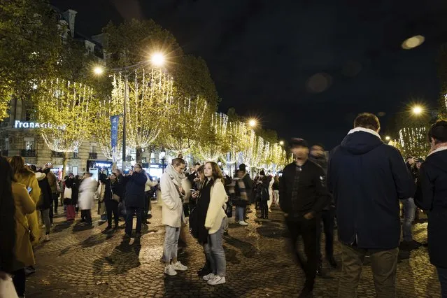 Spectators gather to attend the Champs Elysee Avenue illumination ceremony for the Christmas season, in Paris, November 20, 2022. (Photo by Lewis Joly/AP Photo)