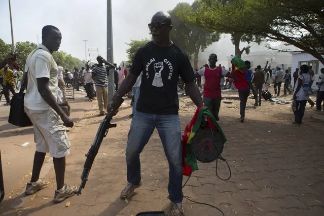 An anti-government protester carries a gun taken from the parliament building in Ouagadougou, capital of Burkina Faso, October 30, 2014. (Photo by Joe Penney/Reuters)