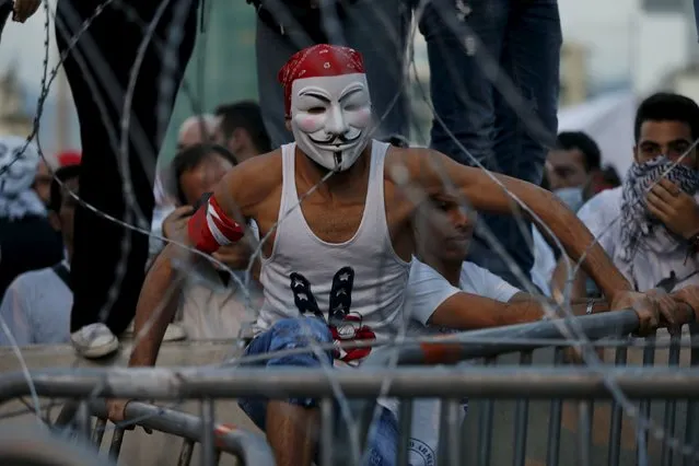 A protester tries to jumps over barbed wire as riot policemen block a street leading to the parliament building during a protest against perceived government failures, including a rubbish disposal crisis, in downtown Beirut, Lebanon October 8, 2015. (Photo by Jamal Saidi/Reuters)