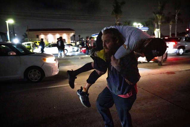 A person carries an injured protester to cover during a protest in Compton, Calif., Saturday, June 7, 2025, after federal immigration authorities conducted operations. (Photo by Ethan Swope/AP Photo)